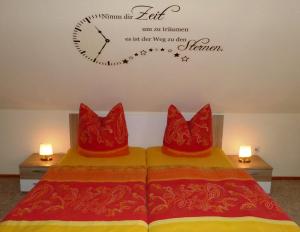 two beds with red pillows and a clock on the wall at Ferienwohnung Heike Greiner in Bischofsgrün