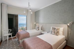 カニコにあるReis Magos IV by An Island Apartのベッド2台とバルコニー付きのホテルの部屋