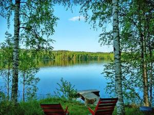 2 Stühle und ein Boot auf einem See in der Unterkunft Holiday Home Siimaranta by Interhome in Vehmersalmi