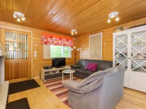 a living room with a couch and a tv at Holiday Home Kiikkukallio by Interhome in Hankamäki