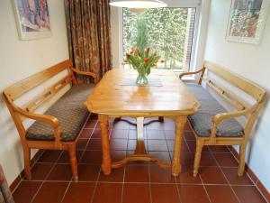 a wooden table with two benches and a vase with flowers at Holiday Home Den Osse by Interhome in Brouwershaven