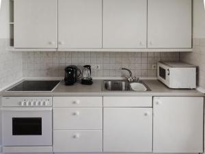 a kitchen with white cabinets and a sink and a microwave at Holiday Home Den Osse by Interhome in Brouwershaven