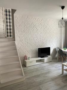 a living room with a tv and a white brick wall at Apartamenty ToTuGdynia 5 in Gdynia