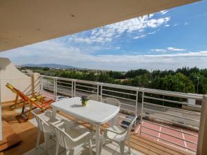 d'un balcon avec une table blanche et des chaises sur le toit. dans l'établissement Apartment Panoramica by Interhome, à Sant Jordi