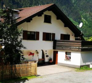 een huis in de bergen met een hek bij Ferienwohnung Waldhaus in Sankt Gallenkirch
