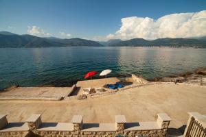 two umbrellas and chairs on the shore of a lake at Leut Apartments in Tivat