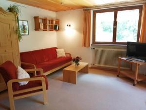 een woonkamer met een rode bank en een tv bij Ferienwohnung Waldhaus in Sankt Gallenkirch