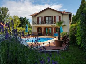 a villa with a swimming pool in front of a house at Hullám Villa B&B in Balatonmáriafürdő