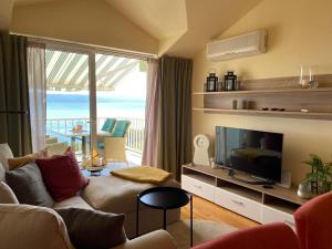 a living room with a couch and a television and a balcony at Werz Sea View Apartment in Brela