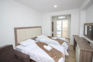a hotel room with three beds and a television at Hotel Cingo in Ohrid