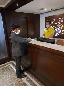 a man wearing a mask standing at a counter at Delta Suites in Durgāpur