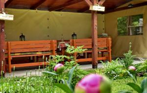 2 bancs en bois dans un jardin fleuri dans l'établissement Illés Vendégház, à Keszthely