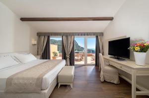 a hotel room with a bed, tv and a window at Boutique Hotel Torre Di Cala Piccola in Porto Santo Stefano