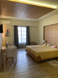 a bedroom with a large bed and a desk at Georges Estates Hotel in Stoupa