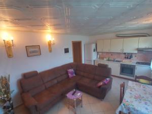 a living room with a brown couch and a kitchen at Apartment Mara in Ankaran
