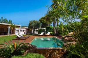 a swimming pool with lounge chairs next to a house at Casa Es Pins in Santa Eularia des Riu