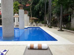 a swimming pool with a chaise lounge next to a resort at Hotel & Spa Hacienda de Cortés in Cuernavaca