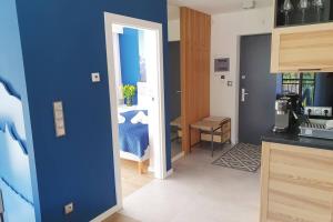 a kitchen with a blue wall and a room with a bed at RelaxApart - Komfortowy apartament z prywatną sauną in Szczyrk
