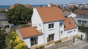 une maison blanche avec un toit orange dans l'établissement Villa les Voiles - Chambres d'hôtes, à Wimereux