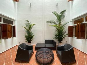 a lobby with chairs and a table and palm trees at Heeren Straits Hotel in Malacca