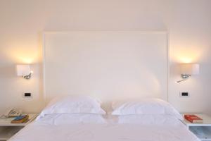 una camera con 2 letti bianchi e 2 lampade di Hotel Bristol a Sorrento