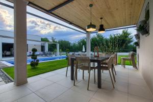 a dining room with a table and chairs on a patio at Luxury design Villa Maell with private pool and high level of privacy in Šišan