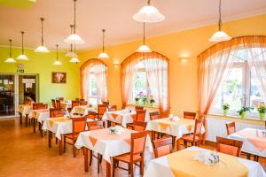a restaurant with white tables and chairs and windows at Villa Sylvia in Dźwirzyno