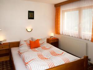 1 dormitorio con 1 cama con almohadas de color naranja y ventana en Apartment Garni Regina - KPL642 by Interhome, en Kappl