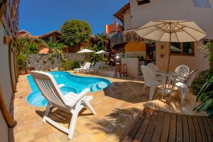 a pool with chairs and a table and an umbrella at Pousada Manga Rosa in Ilhabela