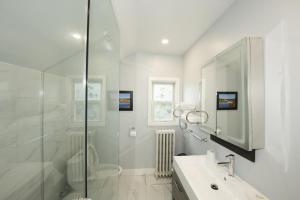 a white bathroom with a shower and a sink at Serene Niagara Inn in Niagara Falls +37 photos