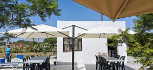 two tables and chairs with umbrellas in front of a building at Retiro dos Batudes in Palmela