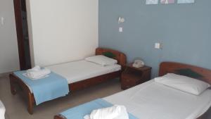a room with two beds and a table with two chairs at Hotel Lena in Limenas
