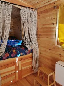 a bedroom in a log cabin with curtains at Roulotte la clé du Luberon in Buoux