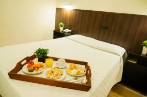 bandeja de comida en una cama en una habitación de hotel en Mediterrâneo Park Hotel, en Três Lagoas
