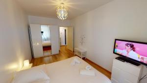 a living room with a white couch and a flat screen tv at Aux bons amis - Parlement/Orangerie in Strasbourg