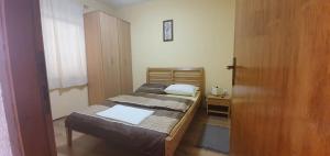 a small bedroom with two beds and a wooden door at Apartments New Charming in Senj