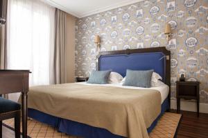 Schlafzimmer mit einem großen Bett mit blauem Kopfteil in der Unterkunft Serotel Lutèce in Paris