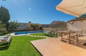 un patio con mesa, sillas y piscina en Villa el Retiro, en Llucmajor