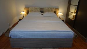 シビウにあるHistorical Houseのランプ2つが備わる客室の大きな白いベッド1台