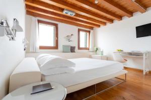 a white bedroom with a large white bed and a table at Venissa Wine Resort in Burano