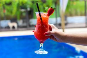 una mano sosteniendo una bebida roja con una fresa en ella en Parque Do Avestruz Eco Resort, en Esmeraldas