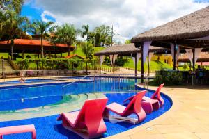 Parque Do Avestruz Eco Resort في إسمرالداس: مسبح وكراسي حمراء ومنتجع
