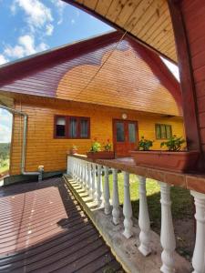 uma casa com um alpendre em madeira com um corrimão branco em Casa Geo em Arieşeni