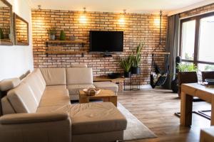 a living room with a couch and a brick wall at Apartament nad jeziorem Drwęckim Oaza in Ostróda