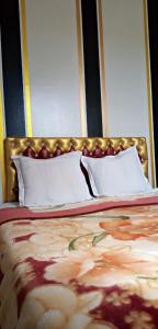 uma cama com cabeceira dourada e almofadas brancas em La casa de Wael em Ifrane