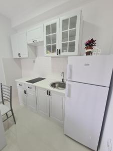 a white kitchen with a sink and a refrigerator at Apartmani Popivoda in Soko Banja