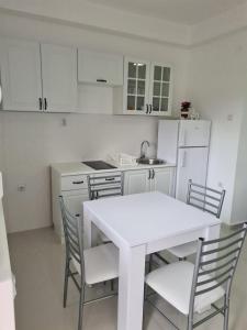 a white kitchen with a white table and chairs at Apartmani Popivoda in Soko Banja