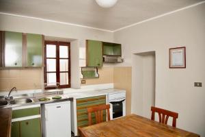 eine Küche mit grünen Schränken und einem Holztisch in der Unterkunft Contempora Apartments - Ca' Brenta Dudù in San Fedele Intelvi