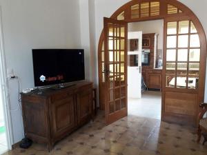 ein Wohnzimmer mit einem Flachbild-TV und einer offenen Tür in der Unterkunft Gîte Le Bois d Argonne in Le Vieil-Dampierre