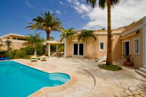 ein Swimmingpool vor einem Haus mit Palmen in der Unterkunft Villa-Tauro Leyh in Mogán